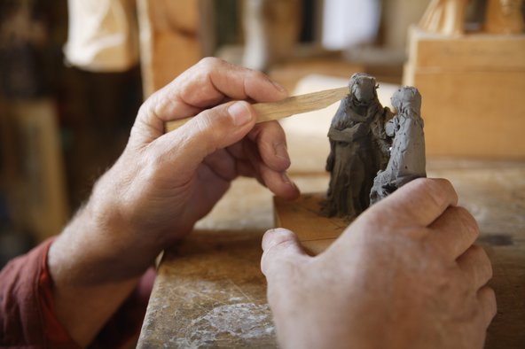 Hands carving a pair of clay figurines