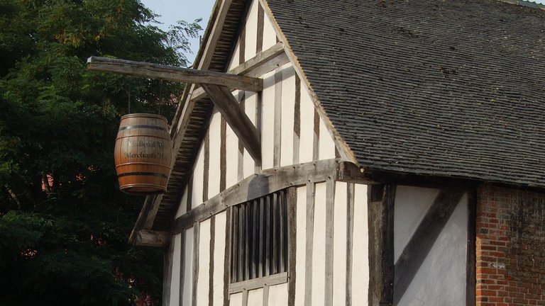 Exterior of a medieval building in Southampton with a barrel hanging from a beam on the first floor